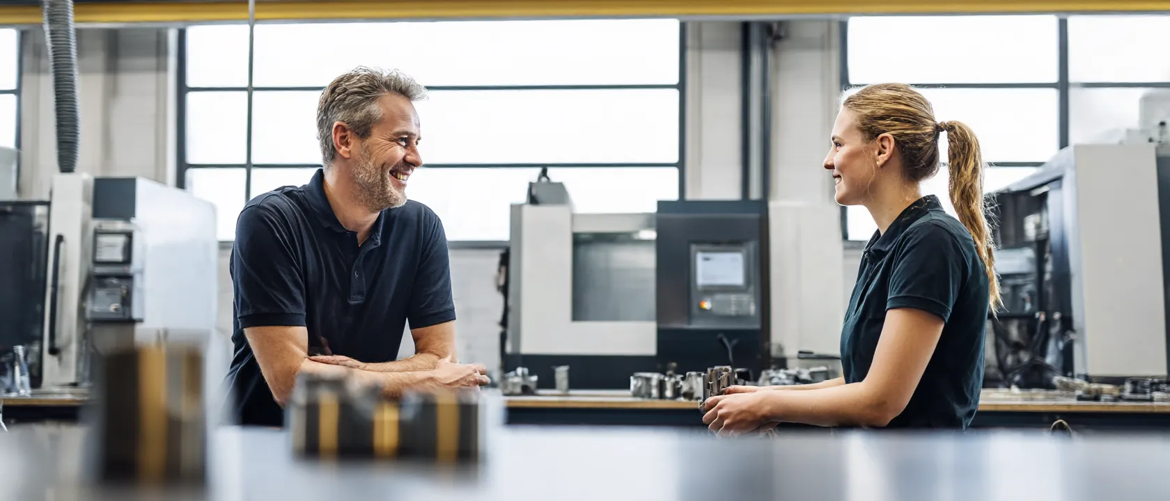 Eigenaar en teamlid in gesprek in hun CNC-werkplaats